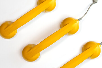Pattern made from yellow color handset of a telephone on a white background.