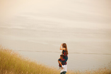 Happy couple standing in a field. Man is holding his woman on shoulders looking at the horizont.
