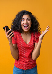 Vertical shot of amazed girl with mobile phone in hands celebrating victory in online casino, hitting jackpot in lotttery, making bets online at bookmaker's website
