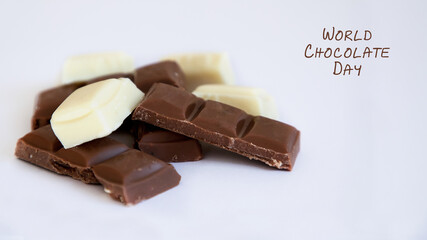 Pieces of black and white chocolate lie on a white background.
