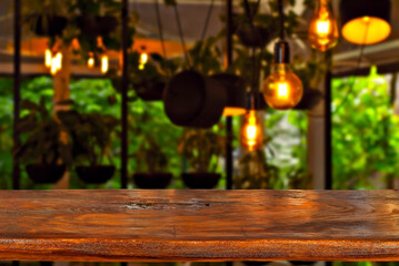 Wooden board on a background of blurred interior with greenery and lamps. Layout for design. Free space for products. Mockup.