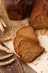Bread in form of triangle and with sunflower seeds near spikelets of wheat lies on old weathered wooden table. Rustic bread and wheat on an old vintage planked wood table. Free text space.