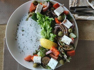 Greek salad is laid out on a white plate with a crescent moon © virin