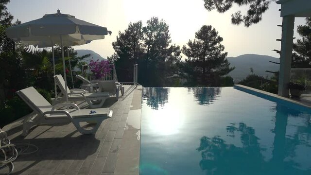 Fethiye, Turkey - 11th of June 2020: 4K Sun light reflects in the water of infinity swimming pool
