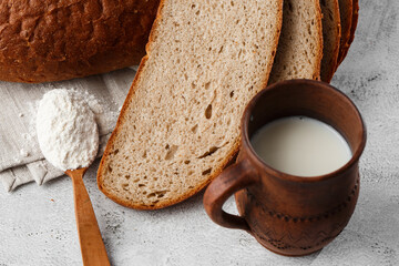 Close-up of homemade bread. Peasant round bread and wheat spikelets with space for text. Homemade baking. Sliced brown bread with sour cream on wooden chopping board wheat rye ears copy space.