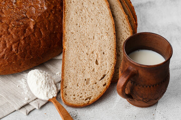 Close-up of homemade bread. Peasant round bread and wheat spikelets with space for text. Homemade baking. Sliced brown bread with sour cream on wooden chopping board wheat rye ears copy space.