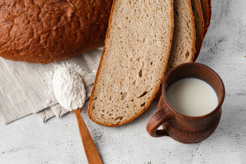 Close-up of homemade bread. Peasant round bread and wheat spikelets with space for text. Homemade baking. Sliced brown bread with sour cream on wooden chopping board wheat rye ears copy space.
