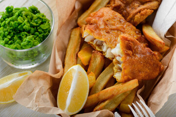 Homemade fish and chips with lemon and green peas