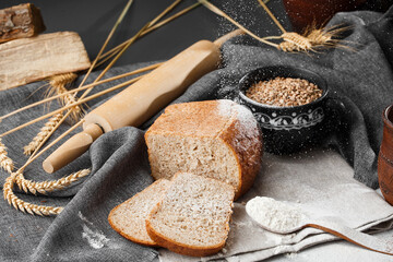 Close-up of homemade bread. Peasant square bread and wheat spikelets with space for text. Homemade baking. Sliced gray bread with flour on wooden chopping board wheat rye ears copy space.
