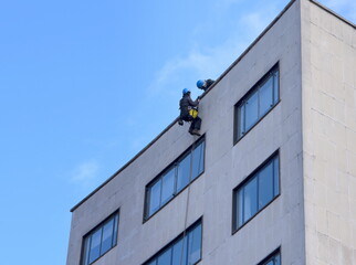 Zwei Bauarbeiter beim Abseilen an der Fassade eines Hochhauses 