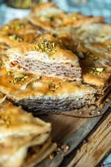 Homemade pistachio baklava triangles on wooden board.