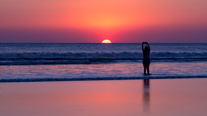 Girl takes a photo of the sunset on the beach