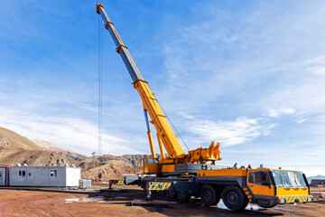 A truck-mounted crane in the construction site. The cranes have two parts. The carrier often...