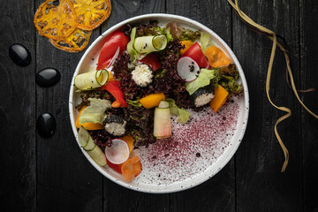 Salad with cheese, pepper, cucumber and sauce on a dark background
