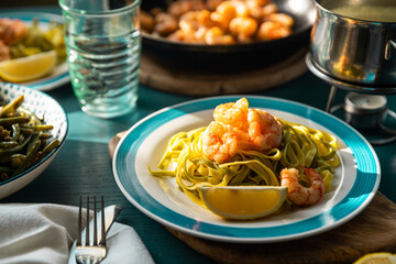 Spinach pasta with grilled shrimps and creamy sauce on served table.