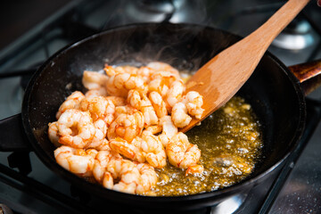Process of frying giant red shrimps with garlic on olive oil on pan.