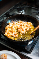 Process of frying giant red shrimps with garlic on olive oil on pan.