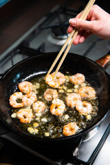 Process of frying giant red shrimps with garlic on olive oil on pan.
