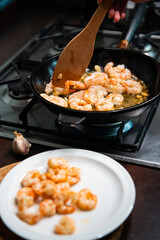 Process of frying giant red shrimps with garlic on olive oil on pan.