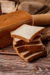 Close-up of homemade bread. Peasant square bread and wheat spikelets with space for text. Homemade baking. White bread with flour and milk on wooden chopping board wheat rye ears copy space.