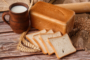 Close-up of homemade bread. Peasant square bread and wheat spikelets with space for text. Homemade baking. White bread with flour and milk on wooden chopping board wheat rye ears copy space.