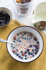 Making breakfast. Homemade granola with nuts, dark chocolate, bilberries and milk.