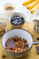 Making breakfast. Homemade granola with nuts, dark chocolate, bilberries and milk.