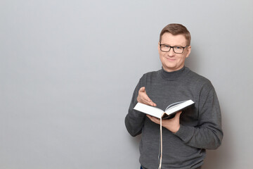 Portrait of cheerful mature man holding open book in hand and smiling