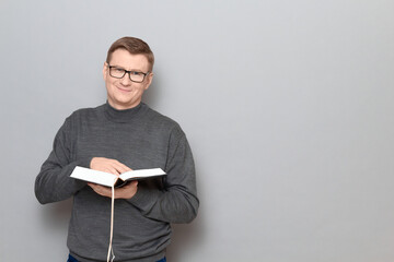 Portrait of happy man holding book in hands and smiling cheerfully