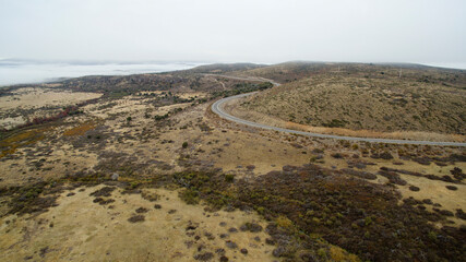 Rural highway. Aerial view of the asphalt road across the yellow meadow and hills in autumn. 