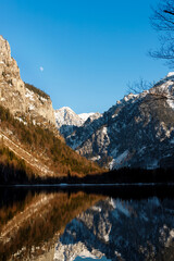 Fototapeta na wymiar beautiful view of mountains with reflection in a alpine lake and moon in blue sky in earley spring