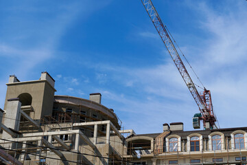 Fototapeta premium modern building under construction, plastered walls and scaffolding, construction crane