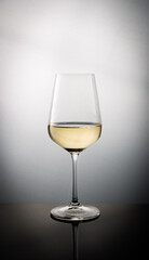 Glass filled with White Wine Reflecting on Dark Surface