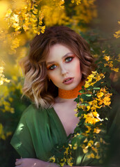 Portrait of a Pretty sensual woman on a background of a yellow blossom tree. Summer time, summer colors.