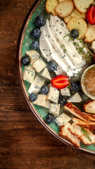 Cheese plate round sliced soft cheese, blueberry, strawberry, and honey on wooden board
