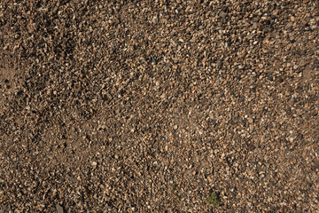 Small stones, pebbles on the ground. Texture. Brown Background