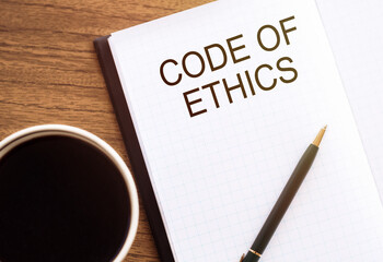 notepad with phrase Code of Ethics on table with coffee