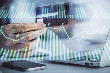 Double exposure of woman on-line shopping holding a credit card and data theme hologram drawing. E-commerce concept.