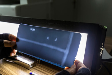 The inspector reviews radyography films of welds of the oil storage tank with light box at the...