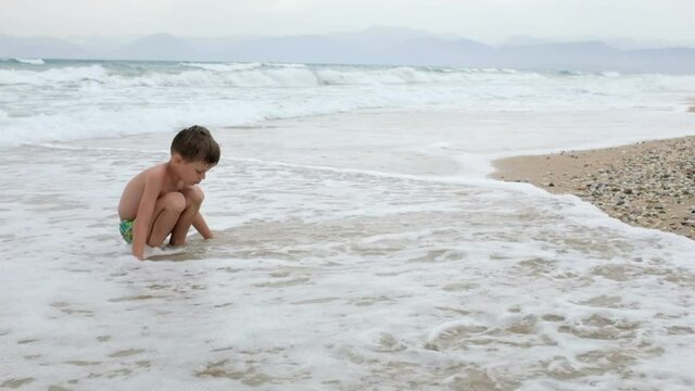 Small boy playing on sandy sandy beach. Crete Island, Greece  