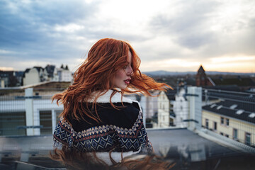 Side view of beautiful young red haired woman in evening light. Nice long wavy red hairs fluttering...