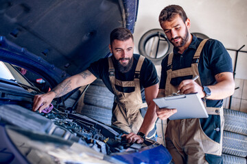 Young mechanics changing oil in car.