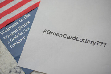 Hashtag Green card Lottery??? on white paper next to Welcome to the United states Guide for New Immigrants.