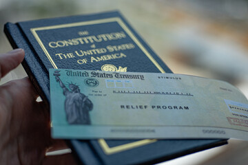 Stimulus check on constitution of United States of America on blurred background.
