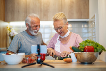 Senior couple recording video for their food blog at kitchen