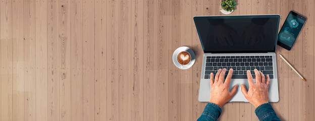 Escritorio madera. Manos sobre un laptop. Realizando tele trabajo