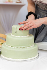 Obraz na płótnie Canvas dreistöckige Torte anschneiden zarte Hände mit lackierten Nägeln