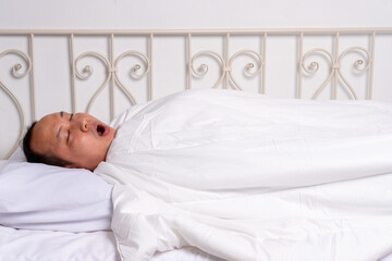 asian Man sleeping in his bed and snoring loudly