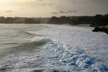 Sunset view with sea wave foam at Batu Bengkung Beach. Exotic paradise in Malang, East Java, Indonesia. Scenic ocean wave view of beach.