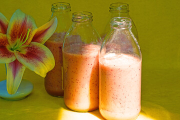 Glass bottles filled with colorful fresh homemade strawberry smoothies